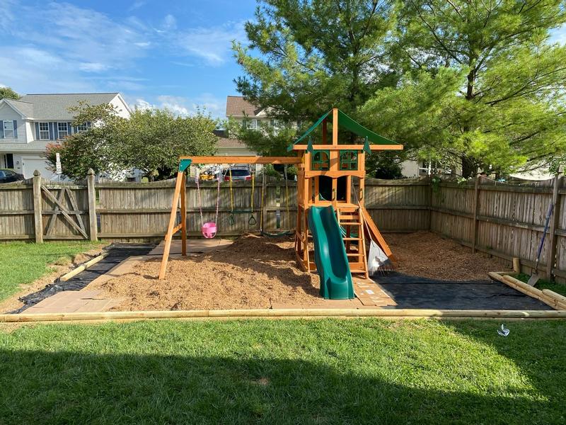 Play set installed with safety mulch and retaining wall being built.